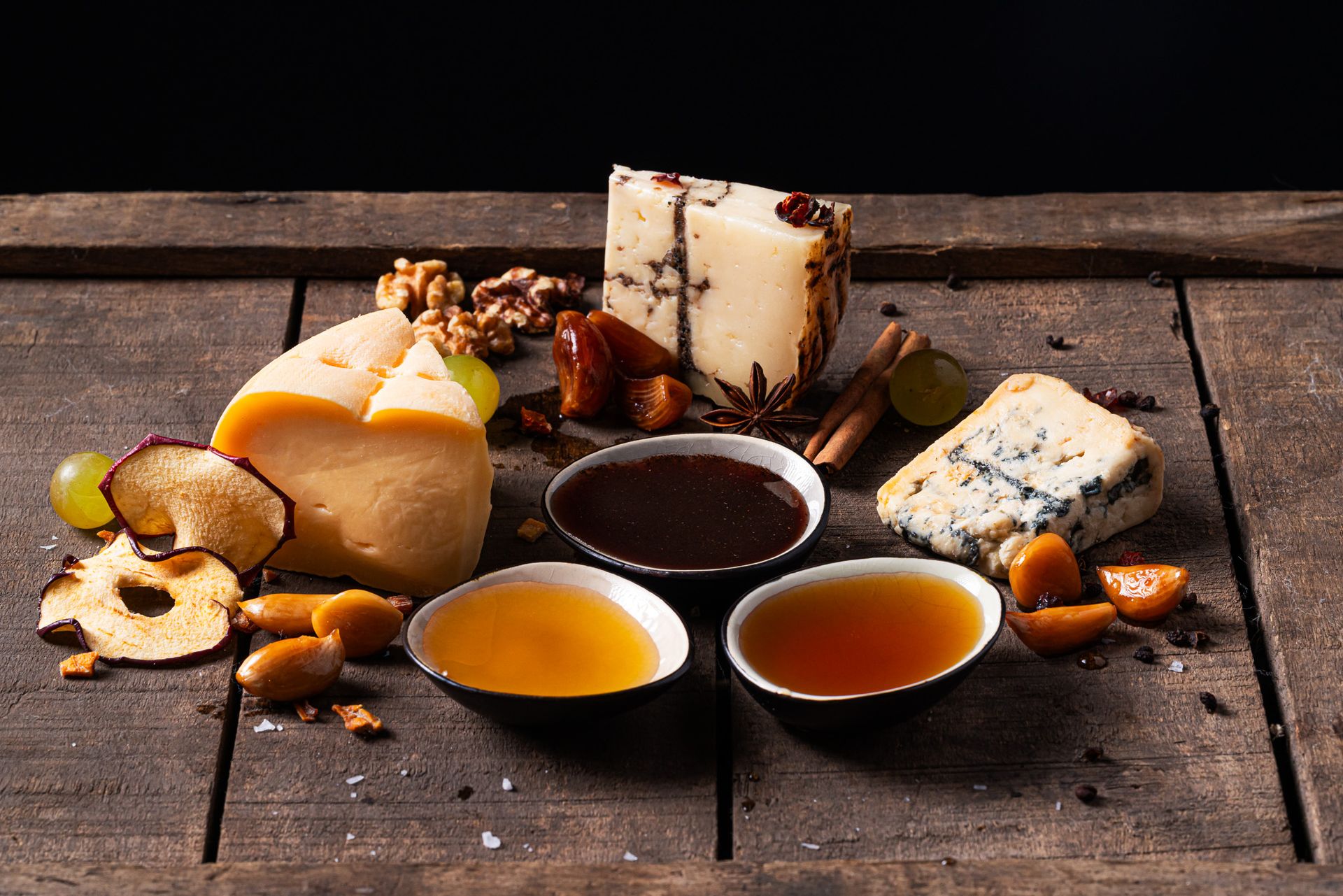 Kaasplank met drie schaaltjes honingsap, druiven en noten