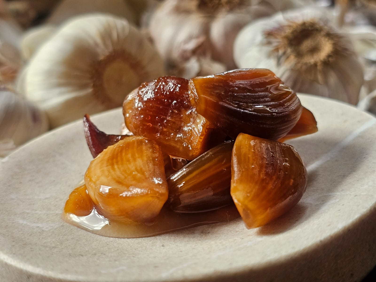 Close-up van amberkleurige gefermenteerde knoflooktenen op een wit keramisch bord