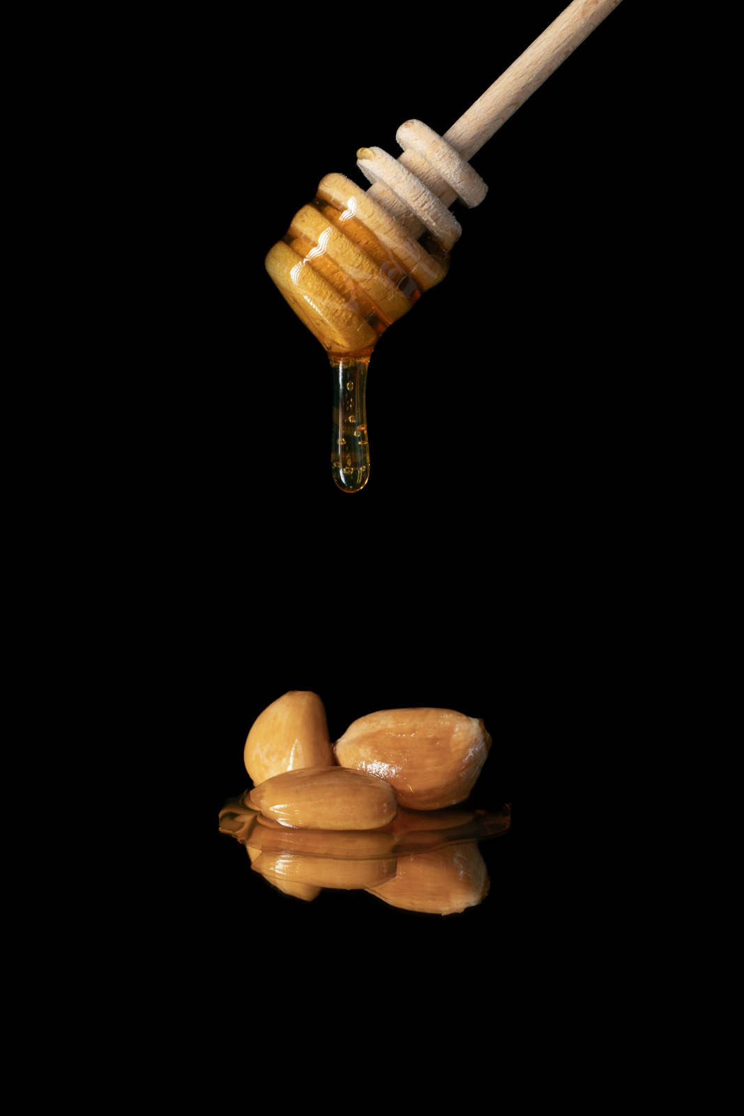 Honingdruppel boven gefermenteerde knoflooktenen — fotografie Ken Stoffels